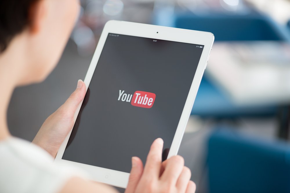 Person holding a tablet. On the tablet is the YouTube logo showing how YouTube Video Marketing is important