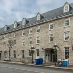 Image of the historic Carriage House on Murray Street in Ottawa's Byward Market. This was the home of the seoplus+ headquarters from 2016-2019. The image is a long historic stone building.