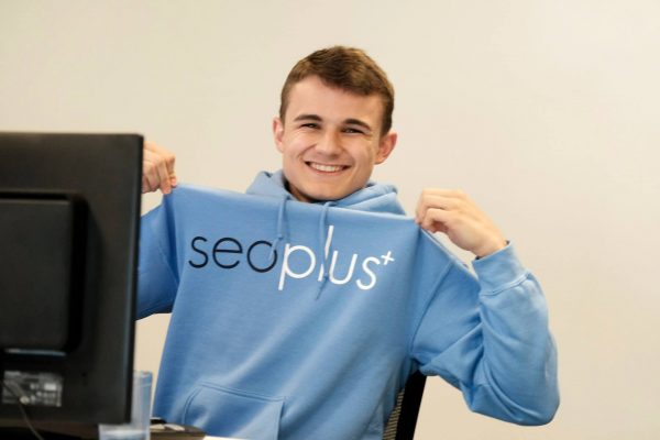 seoplus+ employee smiling and wearing seoplus+ sweater