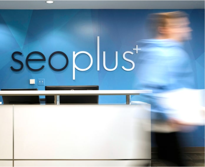 person walking through the seoplus office with the seoplus+ logo on the wall behind